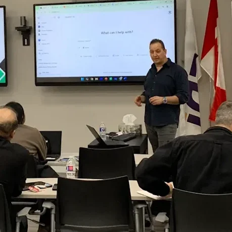 Ran Armon leading an on-site AI session in a GTA boardroom with ChatGPT open on the screen