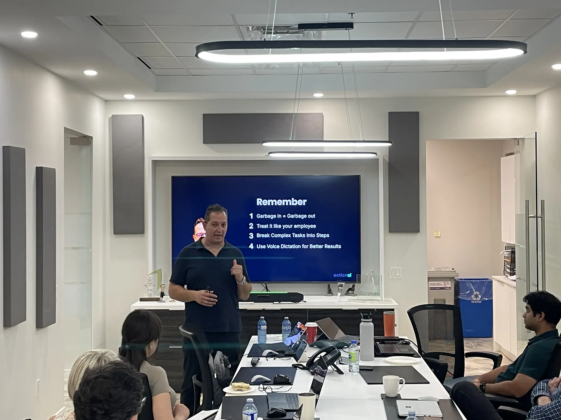 A full AI Lunch and Learn session in a company boardroom in the Greater Toronto Area, team working through prompting on their own laptops
